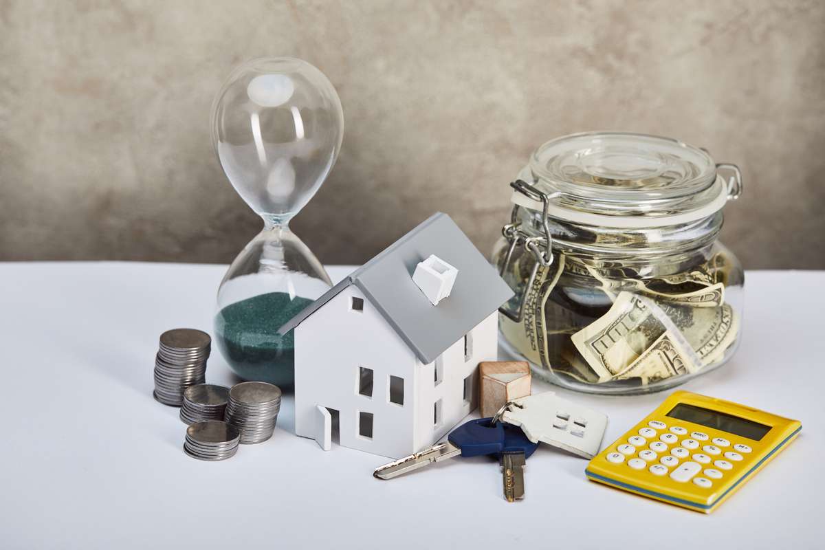 House model with hourglass, calculator, money and keys, real estate concept-1