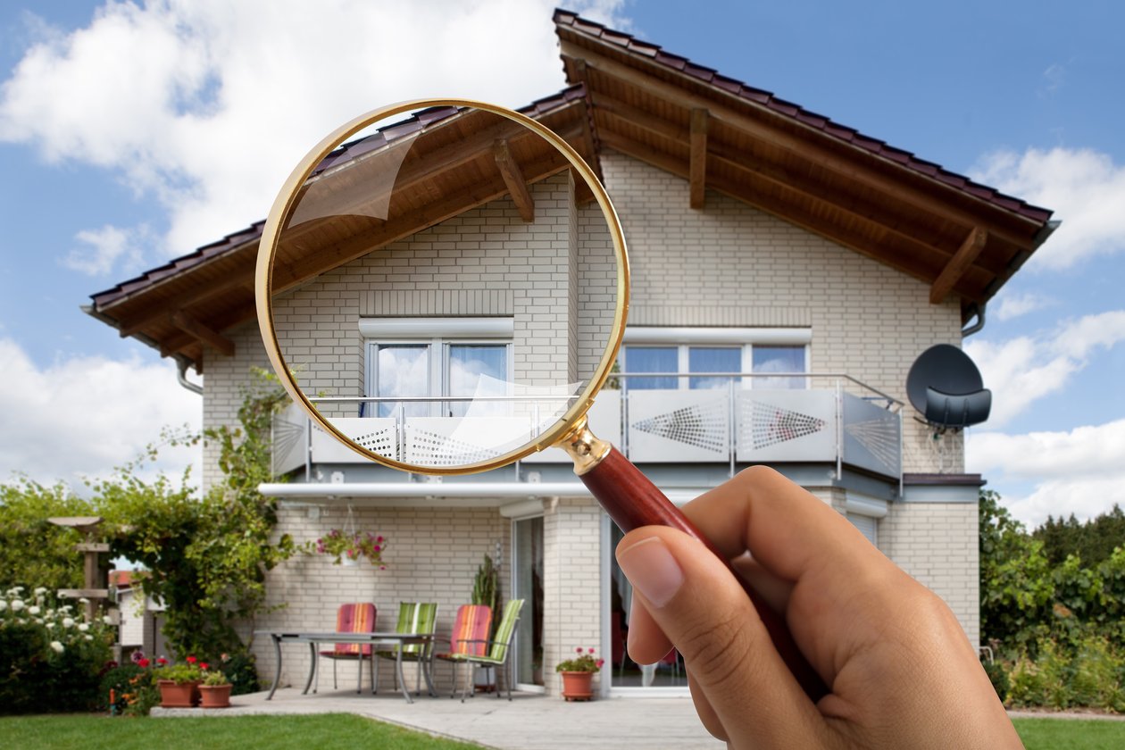 Close-up Of Persons Hand Holding Magnifying Glass Over Luxury House Outdoors