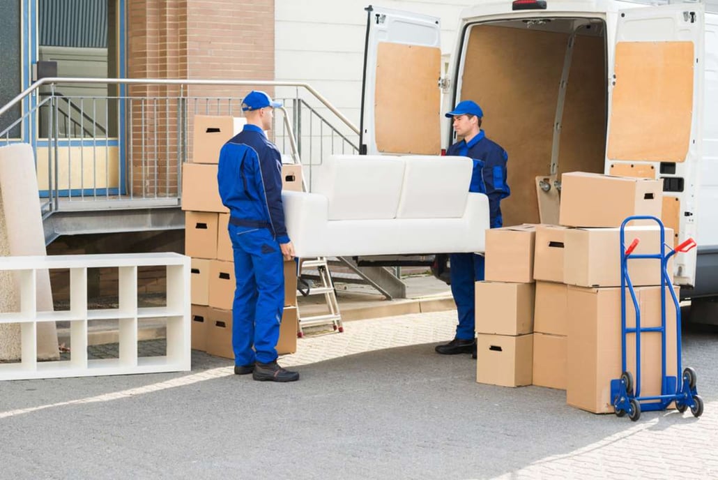Full length of young male movers carrying sofa