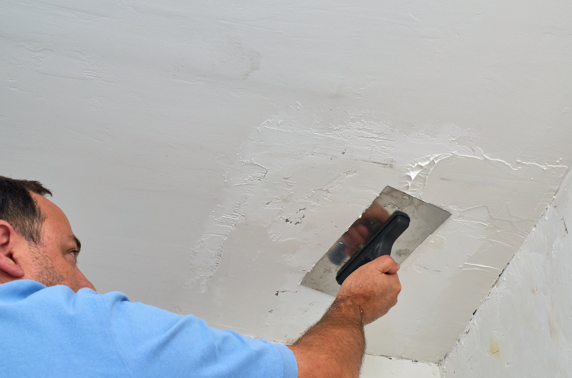 Man smoothing a ceiling with a trowel during renovating works