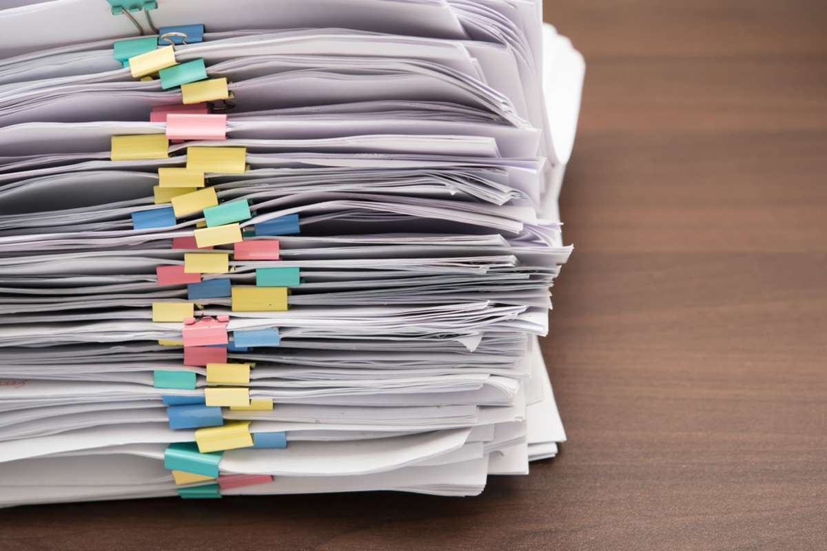 Pile of documents with colorful clips on desk stack up