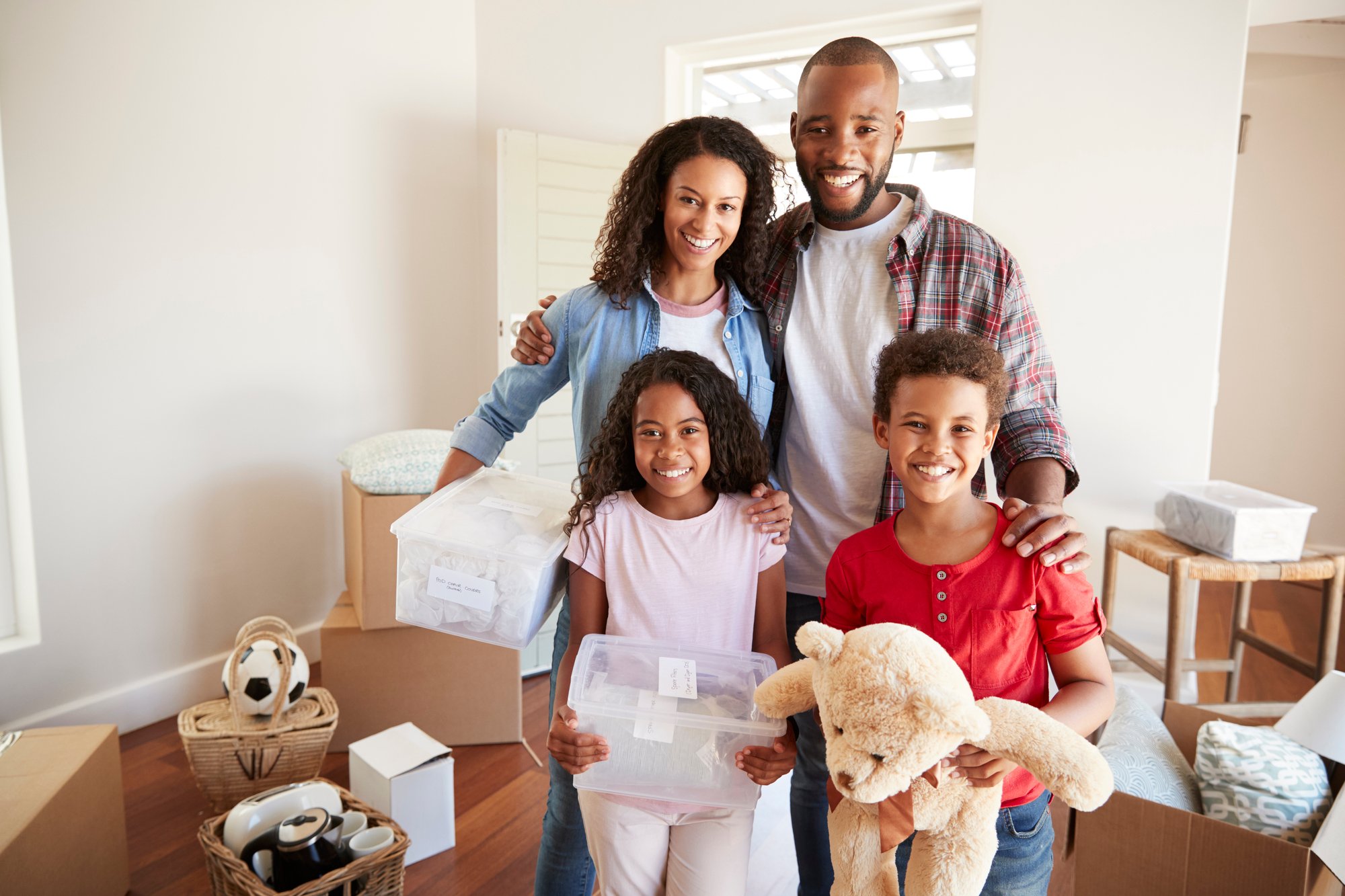 Portrait Of Family Carrying Boxes Into New Home On Moving Day