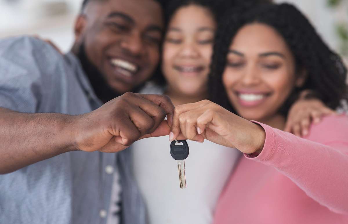 Smiling black family of three holding keys from their new flat (R) (S)