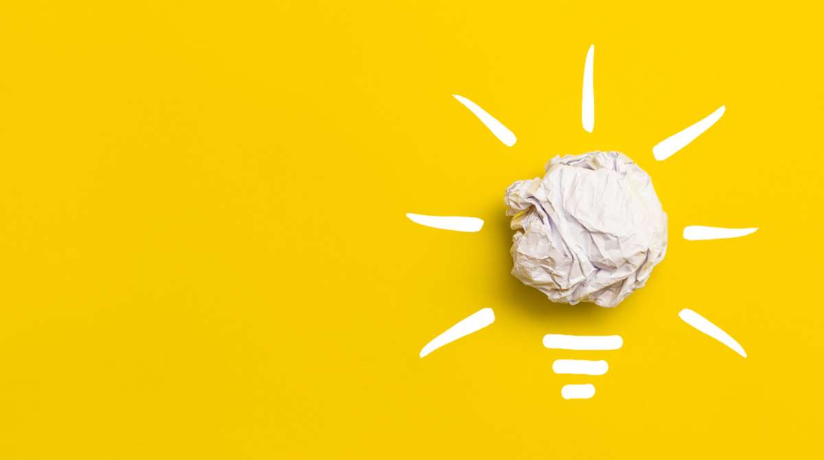 Light bulb with crumpled paper on yellow background