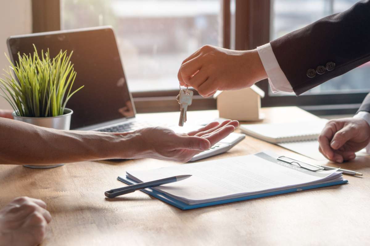 Realtor agent giving a key of apartment to new owner after signed lease agreement