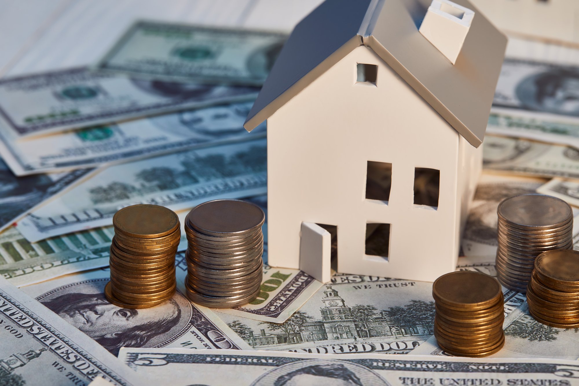 White house model on dollar banknotes with coins, real estate concept