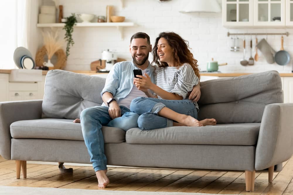 Happy young woman and man hugging and sitting on couch.
